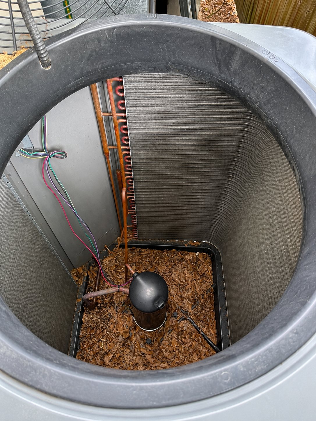 A/C cabinet packed with fallen leaves and debris before cleaning